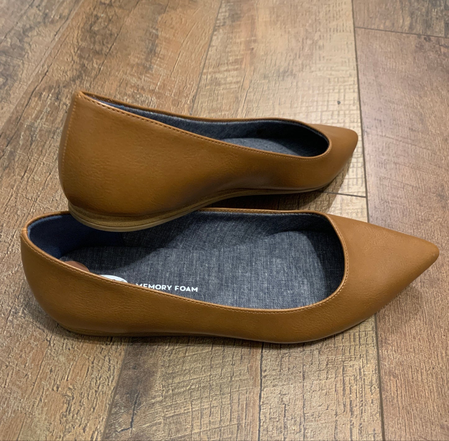 A pair of tan leather pointed-toe flats with a dark gray fabric lining.