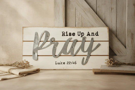 Wooden sign with 'Rise Up And Pray' and Bible verse on a wooden surface.